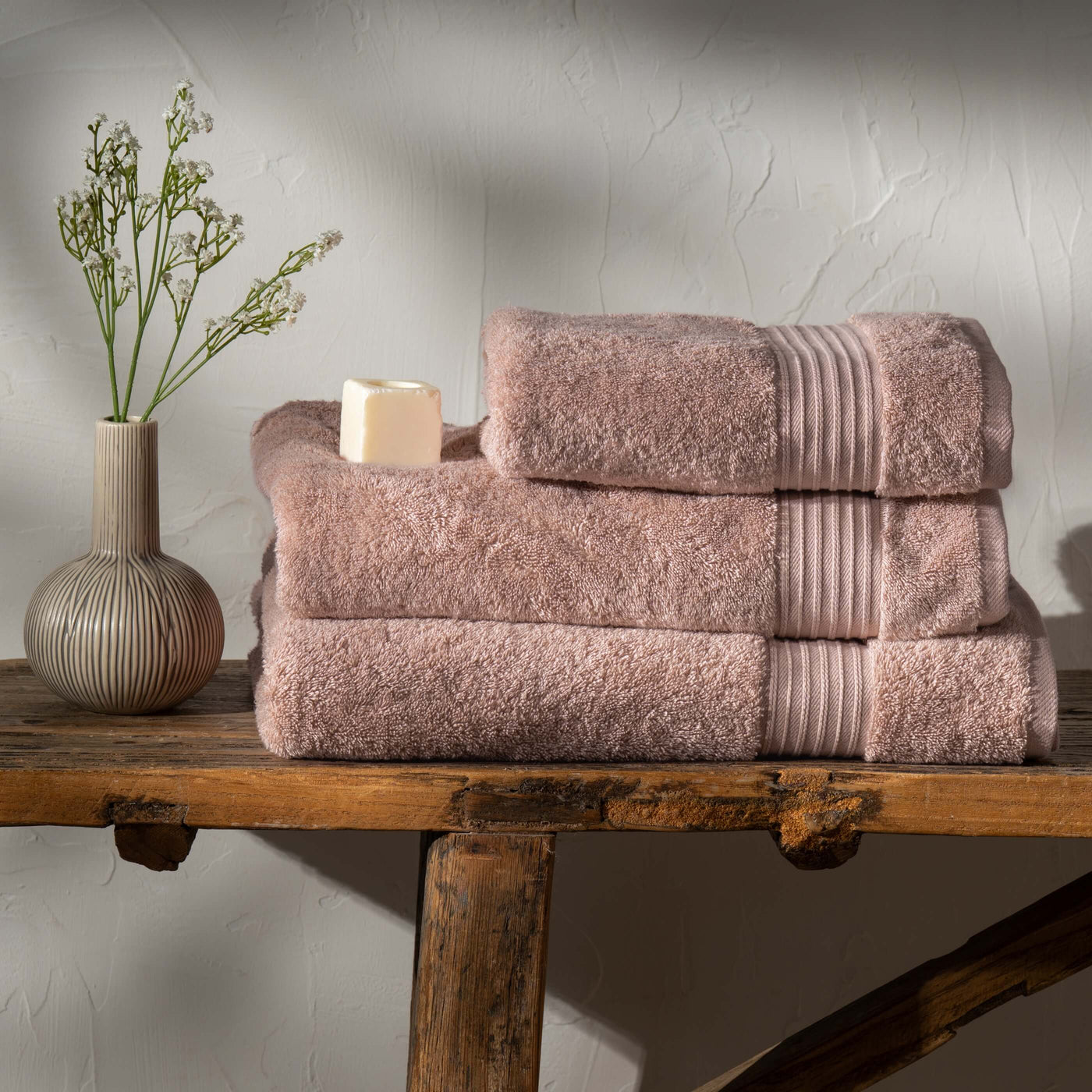 Soft Pink Egyptian Cotton Towels styled in a bedroom | Soak and Sleep