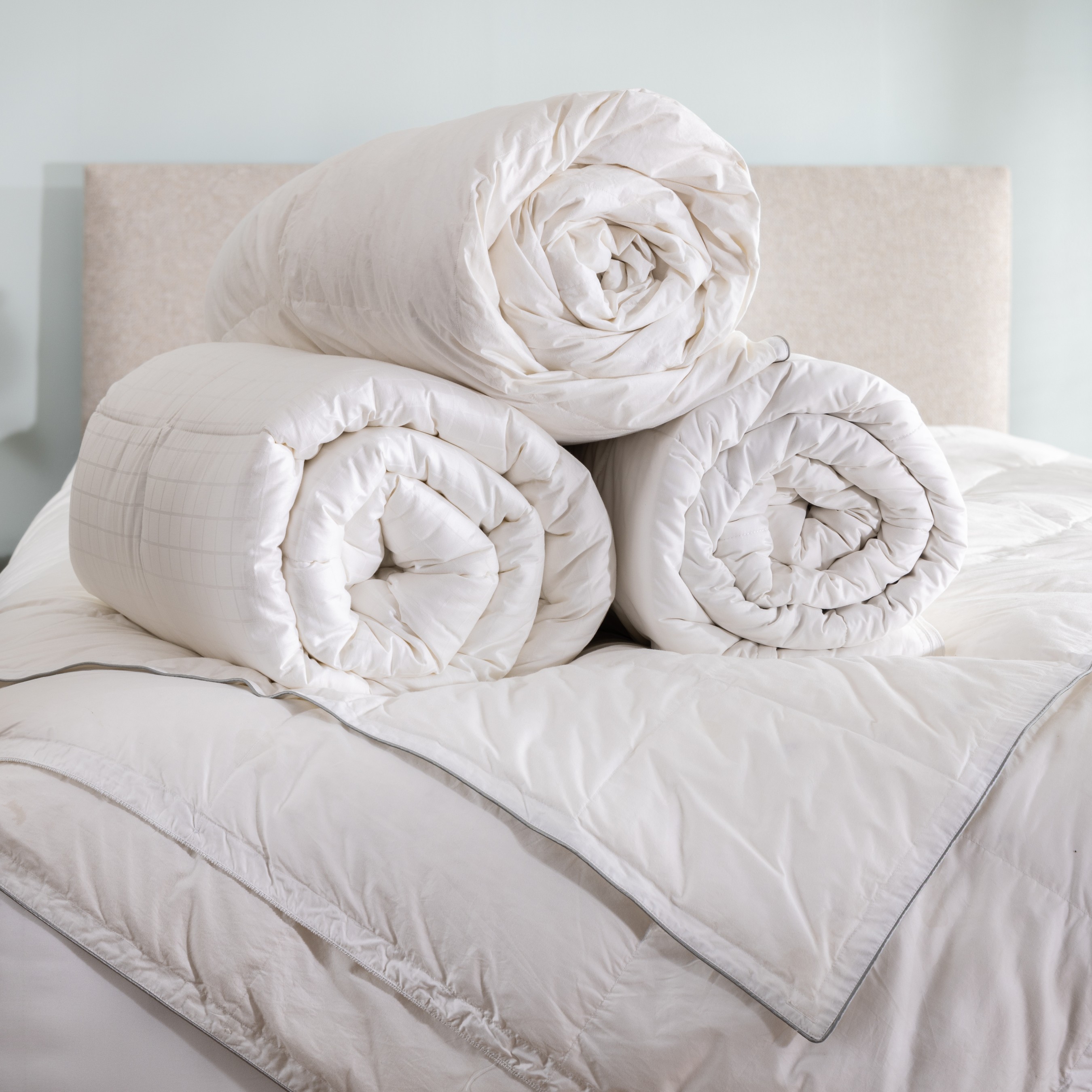 Variation of rolled up Soak&Sleep duvets, rolled and styled on a bed