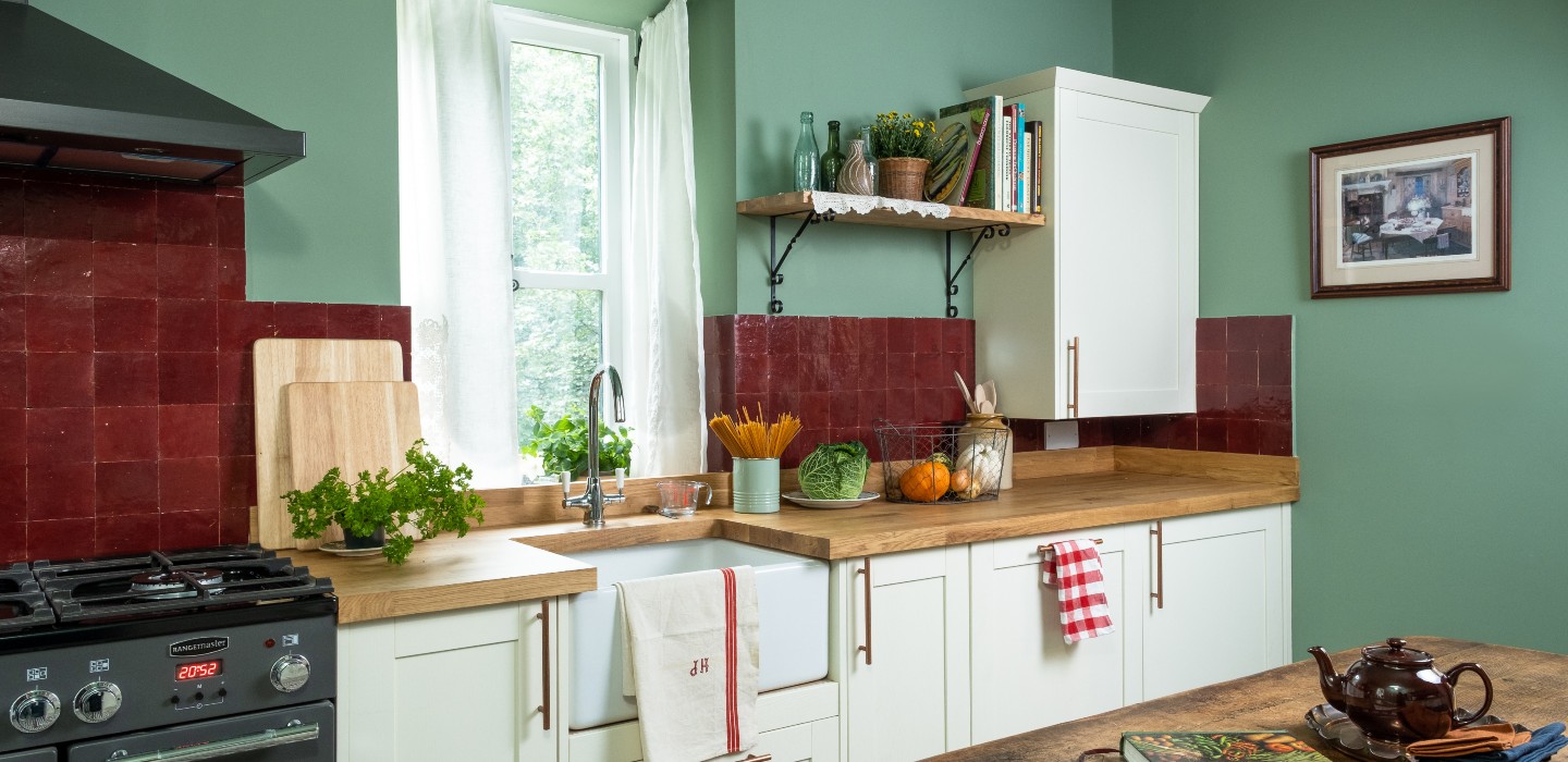 The kitchen has a cosy cottage feel, with gorgeous Victorian-style tiles, cream units and light green walls.