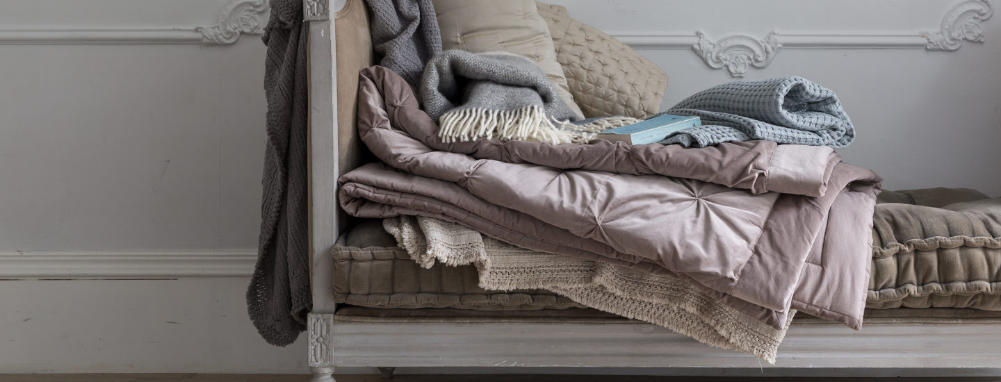 Blankets and throws draped over vintage bench