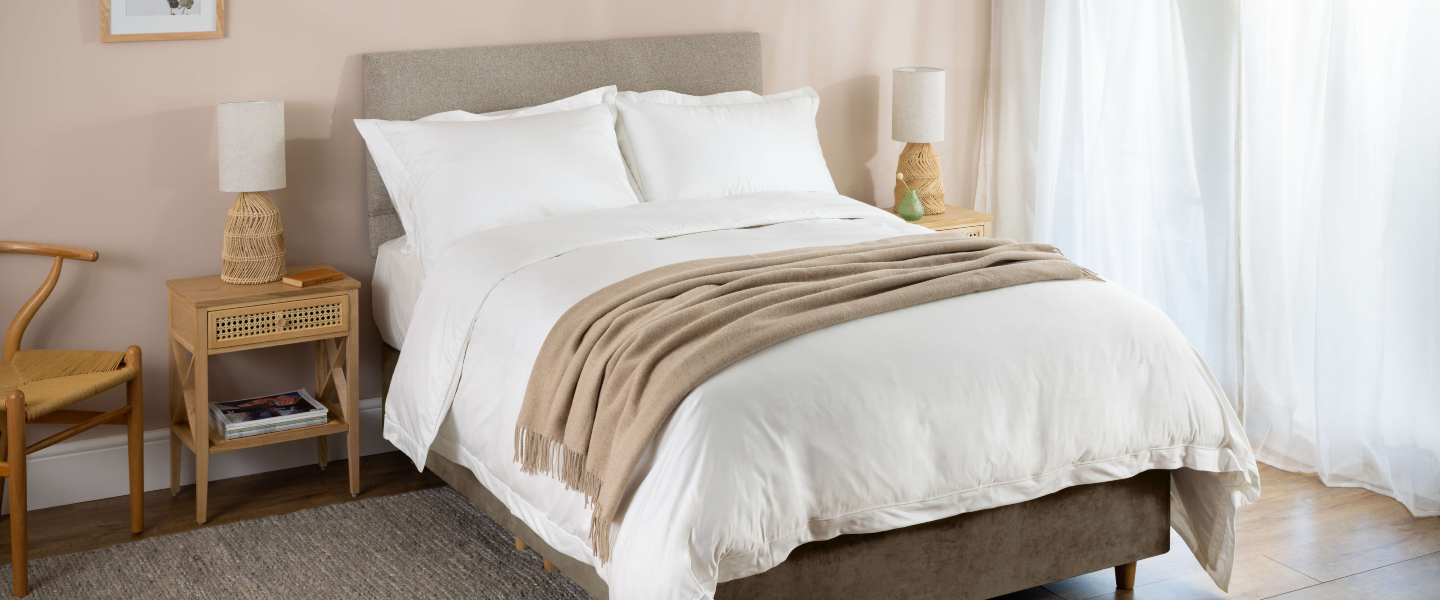 Natural Wool with Cashmere coloured throw, draped over the end of a bed of white Soak&Sleep bedlinen. 