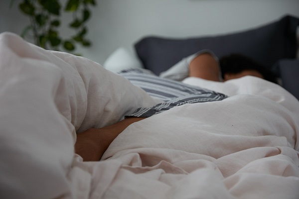 woman sleeping on side with leg over duvet cover